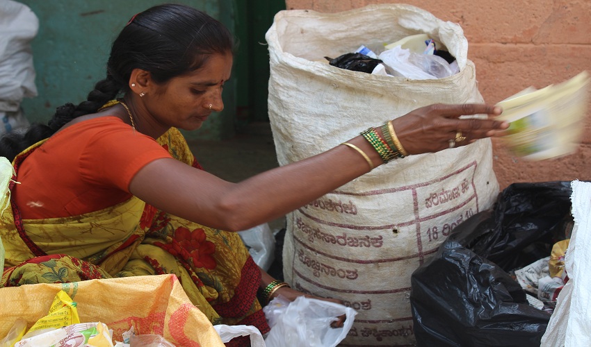 Woman sorting recyclable plastic waste into collection bags to support recycling and sustainable waste management.