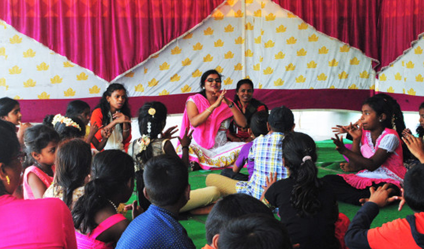 Community educator leading an interactive learning session with children to promote education and social development.